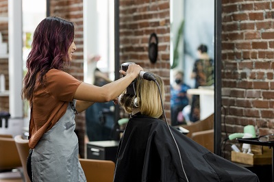 Hairstylist curling the client's hair at a beauty salon